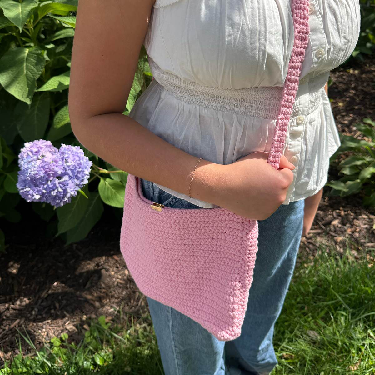 A crocheted crossbody purse worn over a white top and jeans